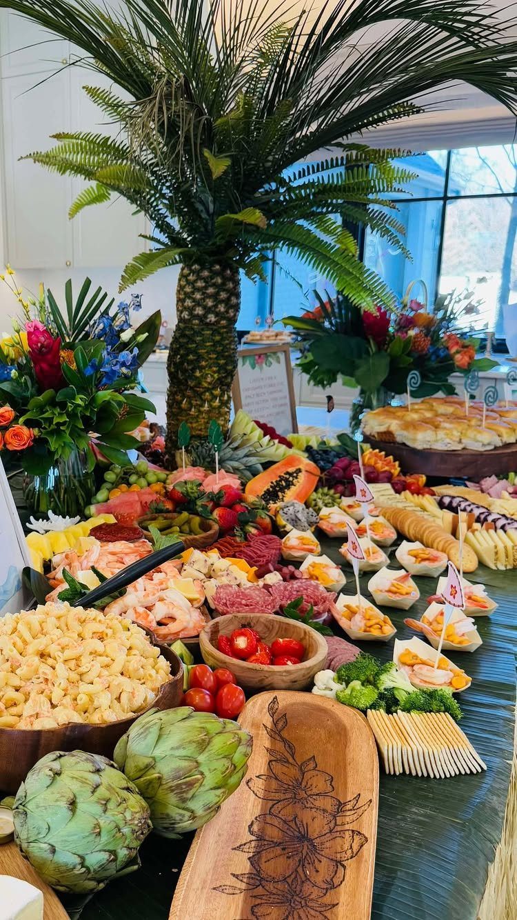 Tropical luau food spread with a pineapple palm tree centerpiece and fresh appetizers.