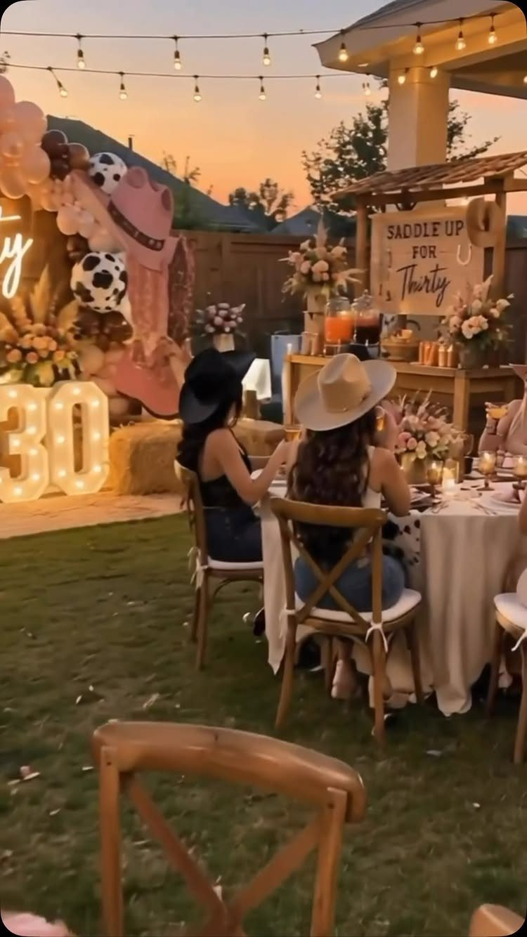 Two women in cowboy hats at a 30th birthday party with western decor.