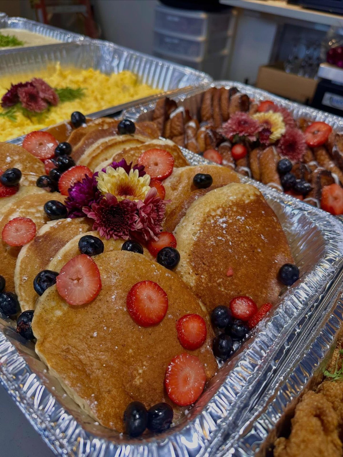 Pancakes with strawberries and blueberries in aluminum trays for a brunch celebration.