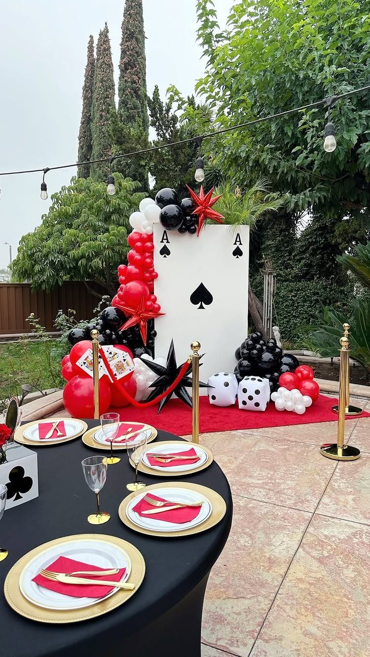 Casino themed party setup with ace of spades backdrop, balloons, and set table.