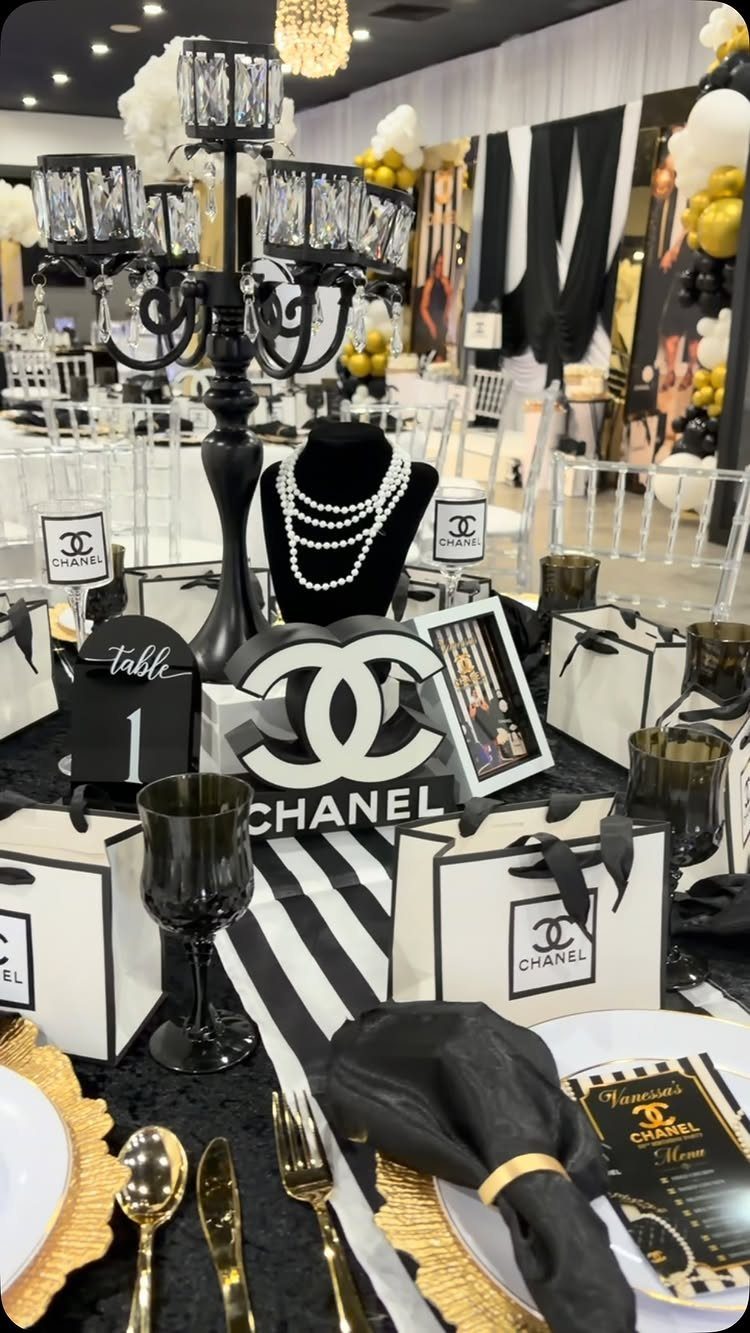 Chanel themed party table with black and white decor, branded bags, and pearls.