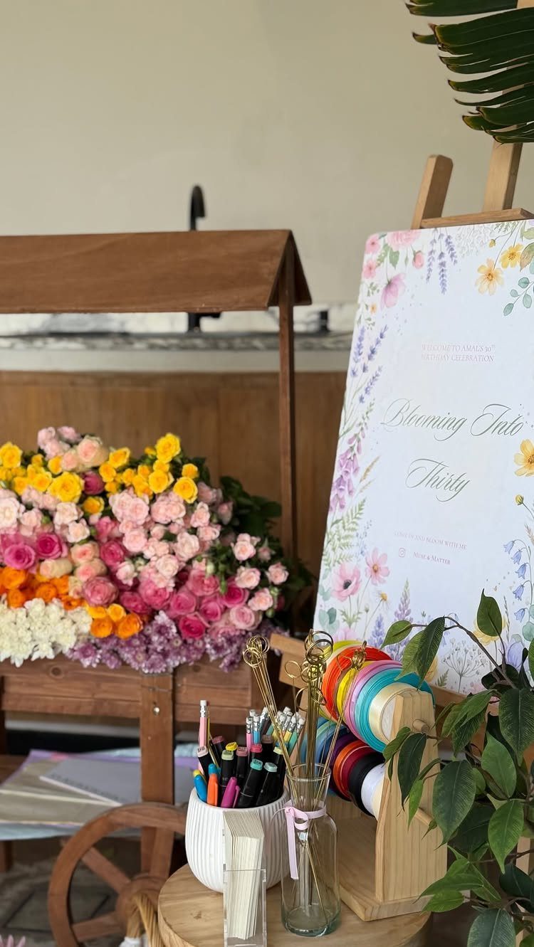 Floral arrangement and art supplies next to a welcome sign for a thirtieth birthday.