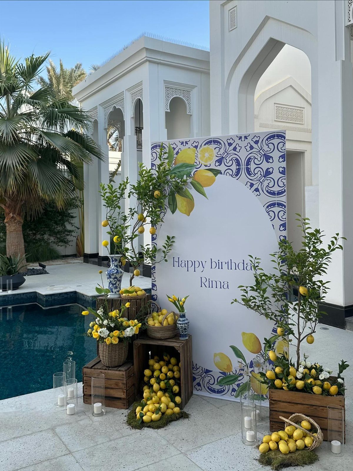 Lemon-themed birthday party setup with lemon trees, crates of lemons, and blue patterns.