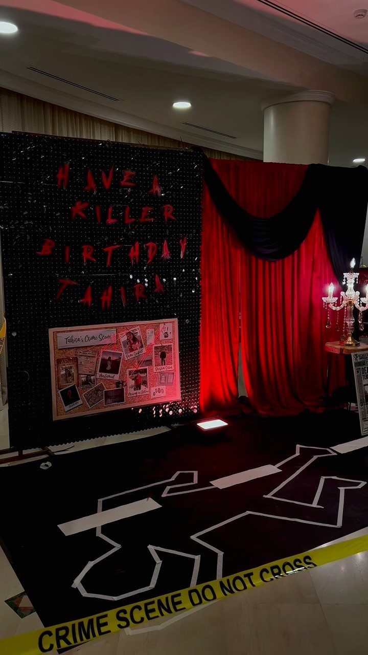 Crime scene themed birthday party setup with red curtains and floor outline.