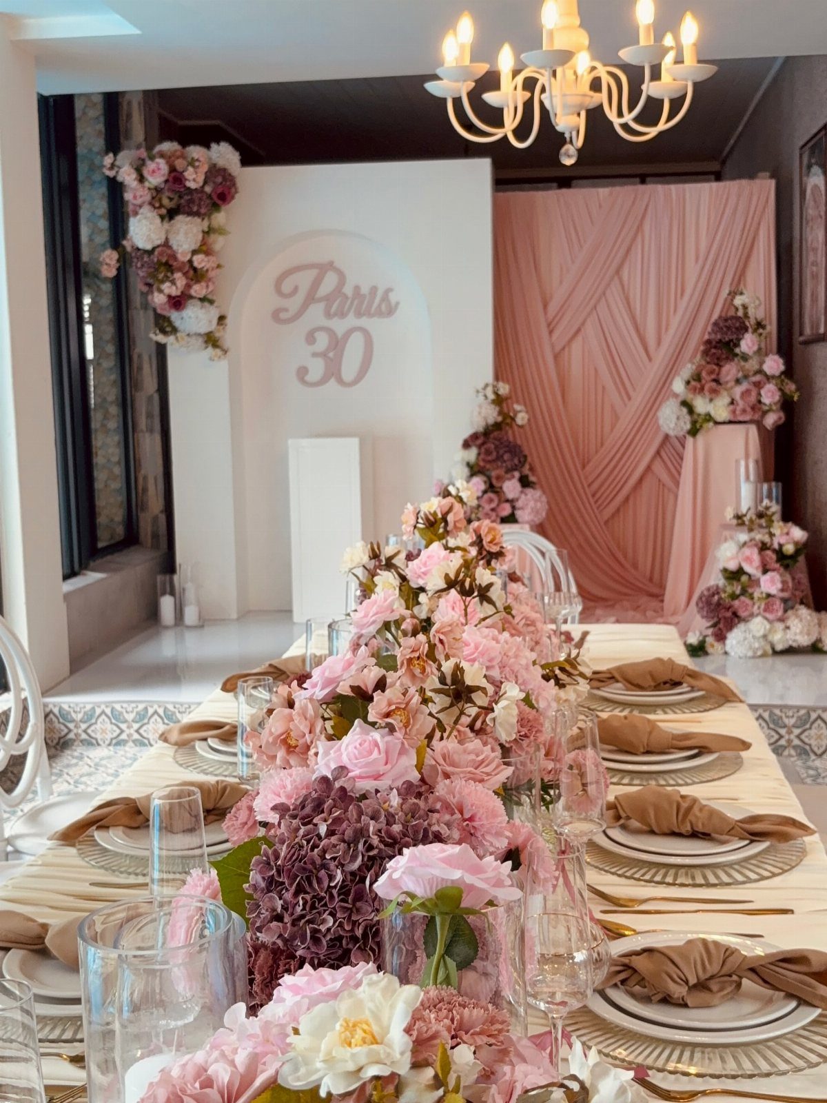 Elegant dining table with pink floral runner and Parisian themed 30th birthday backdrop.