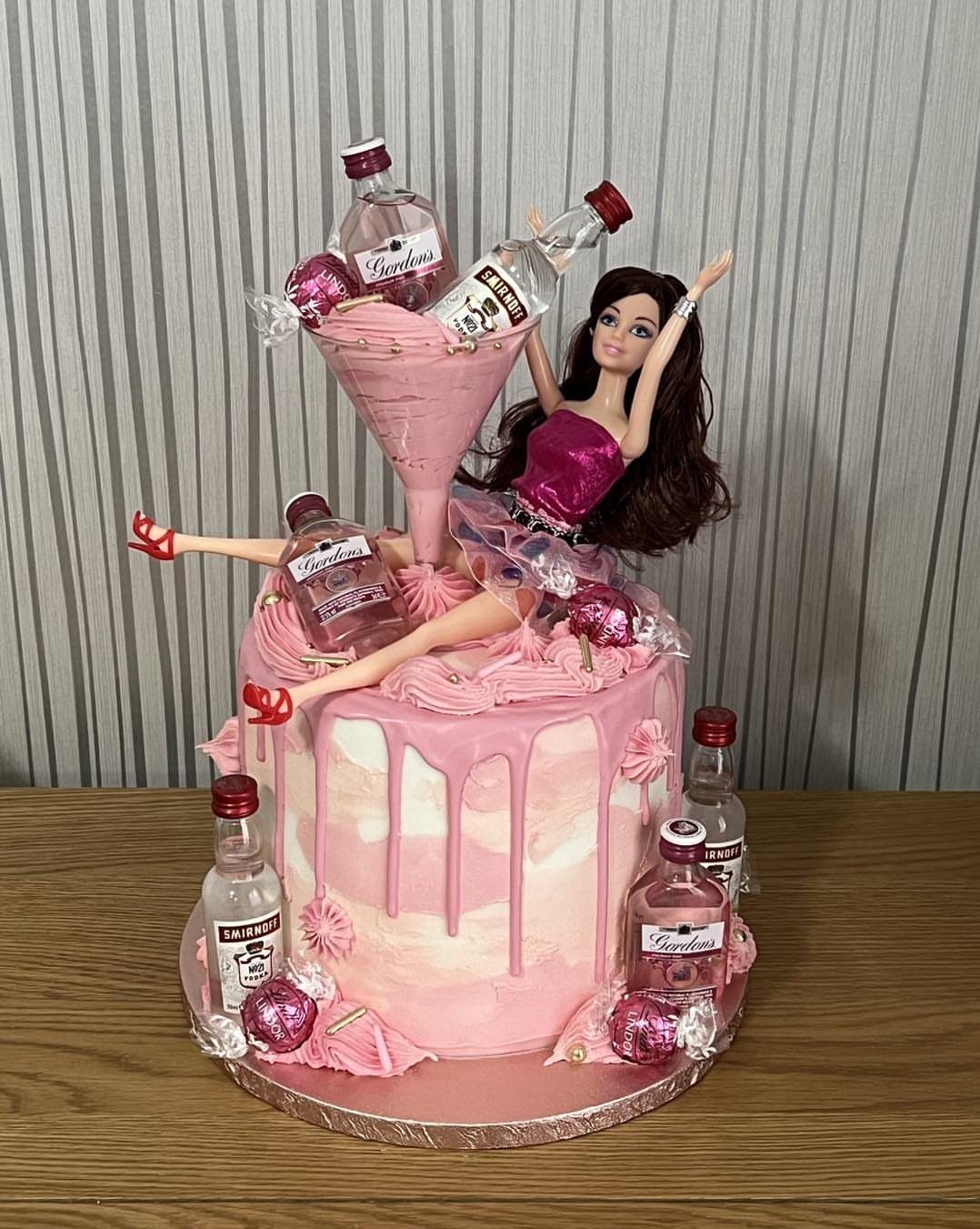 Pink Barbie cake with a martini glass and miniature liquor bottles on top.
