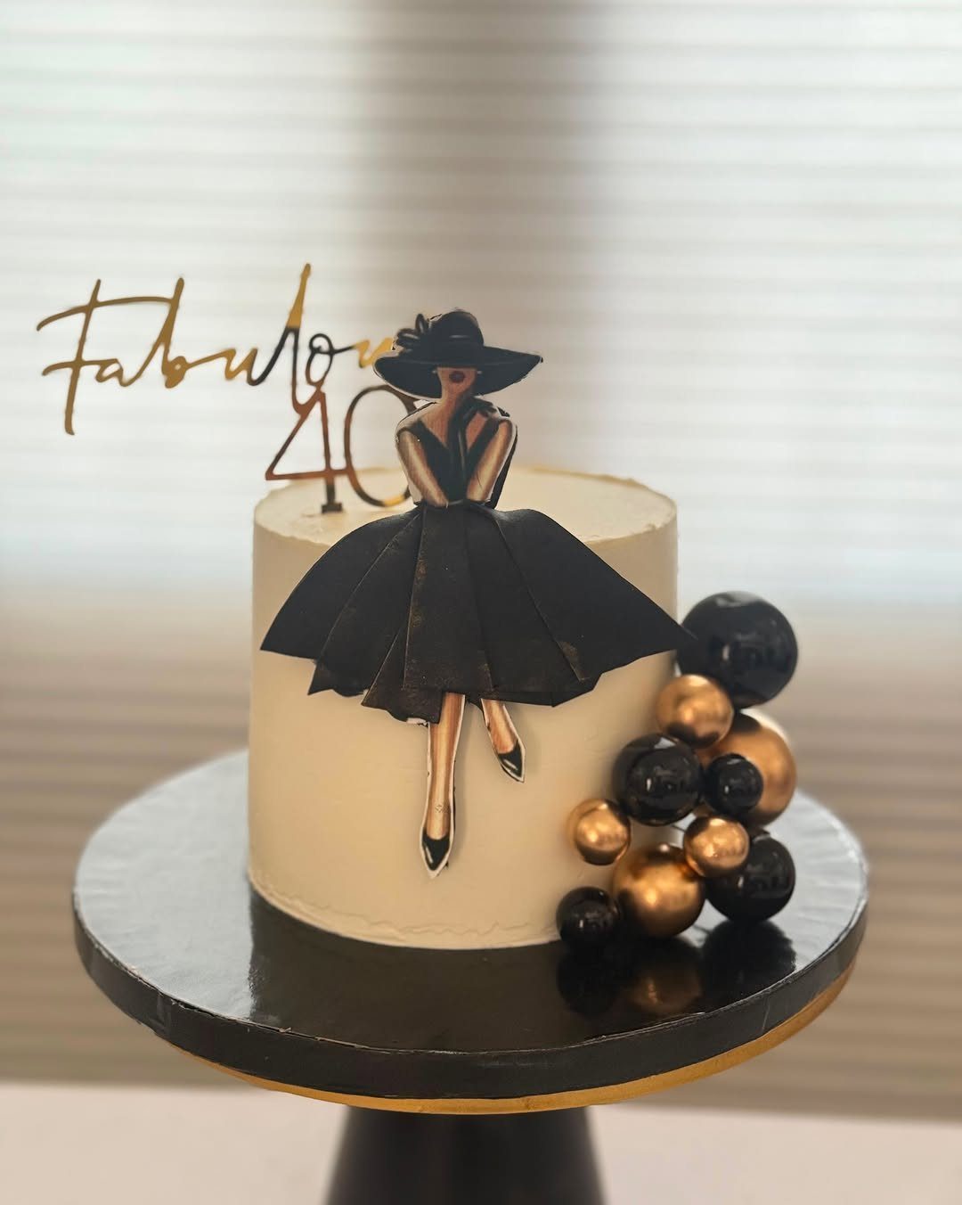 Cream-colored birthday cake with a black woman silhouette topper and gold 40 text.