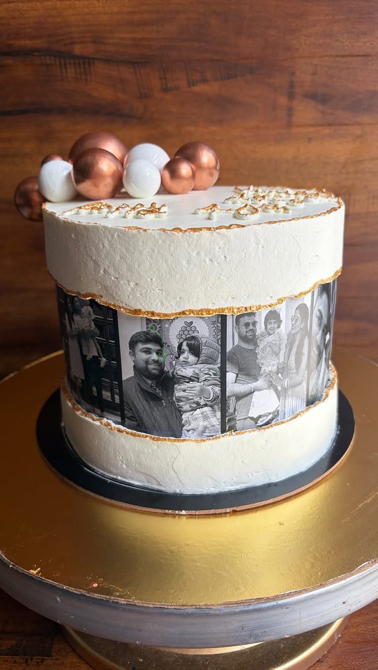 White frosted cake with a wrap of personal photos and copper sphere decorations.