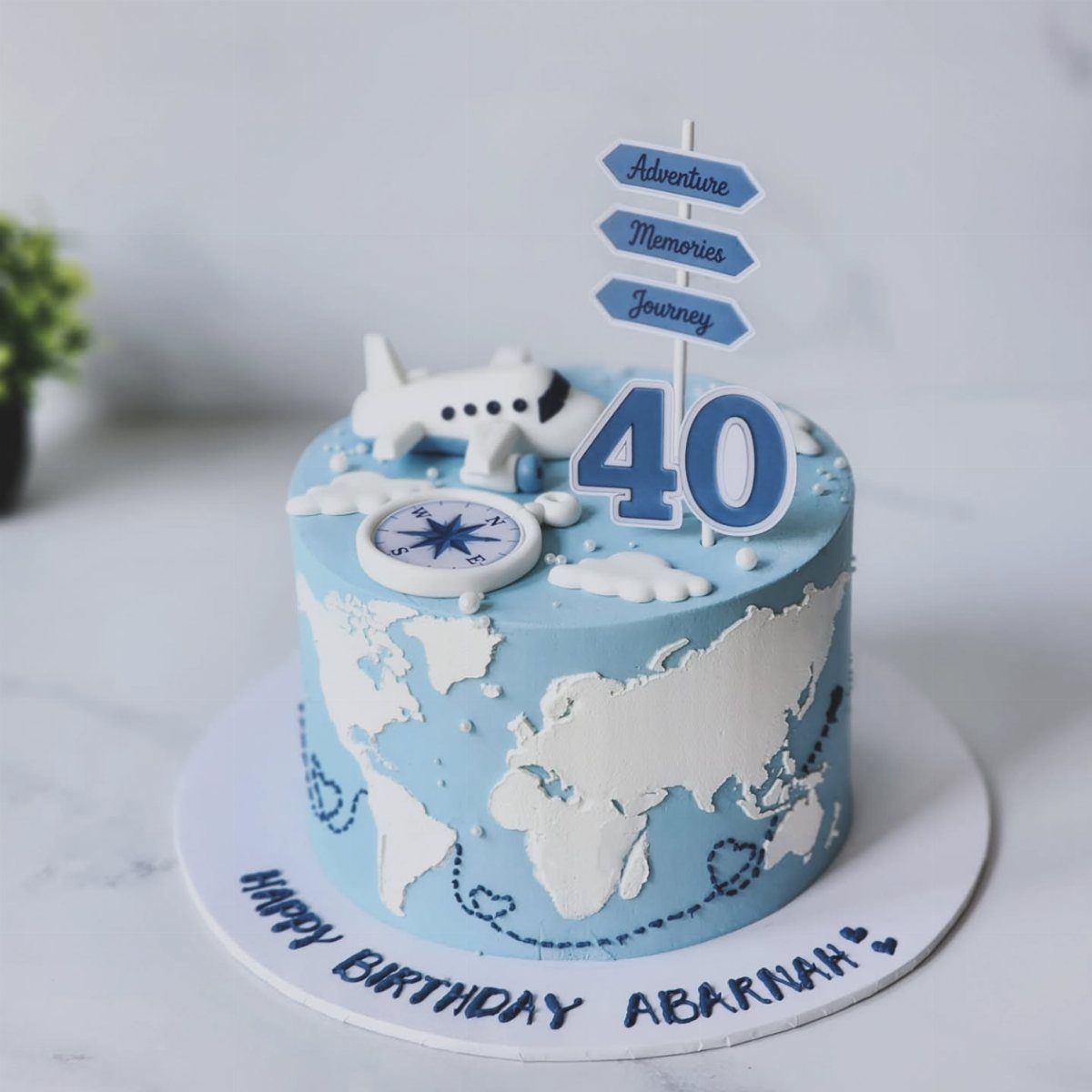 Travel-themed 40th birthday cake with world map, airplane, and adventure signpost.