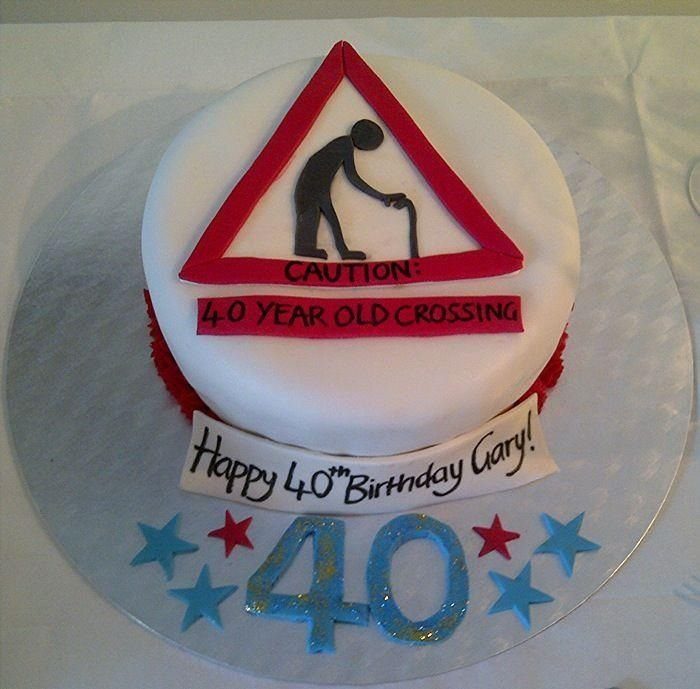 White birthday cake with a red caution sign and 40th birthday decorations.