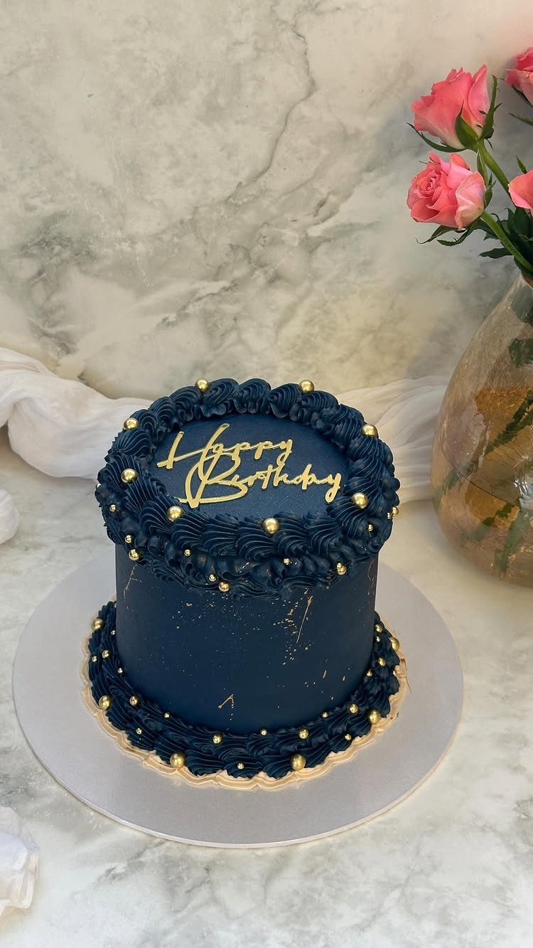 Navy blue frosted birthday cake with gold pearls and a Happy Birthday topper.