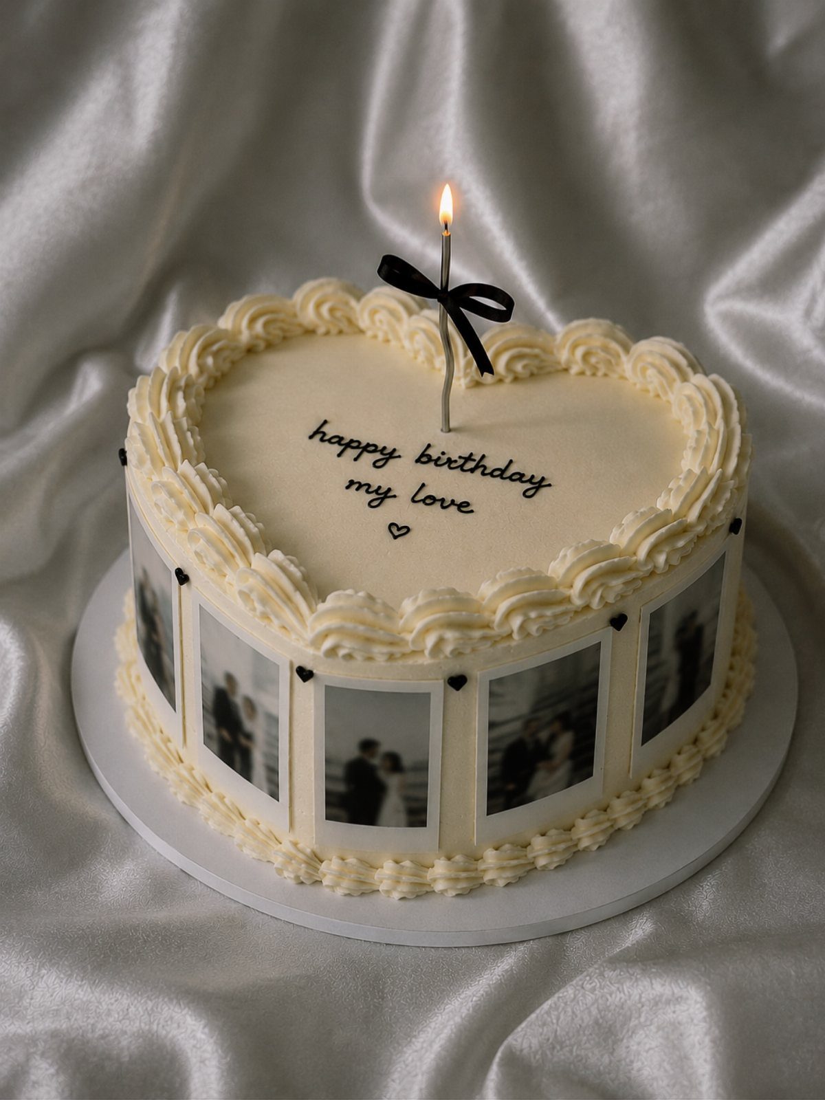 Heart-shaped white cake with edible Polaroid photos on the sides and a candle.