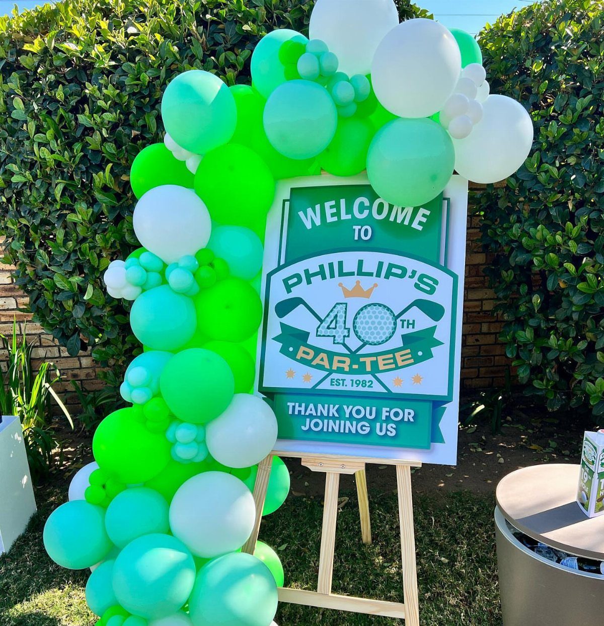 Welcome sign for a 40th golf party with green and white balloon arch.