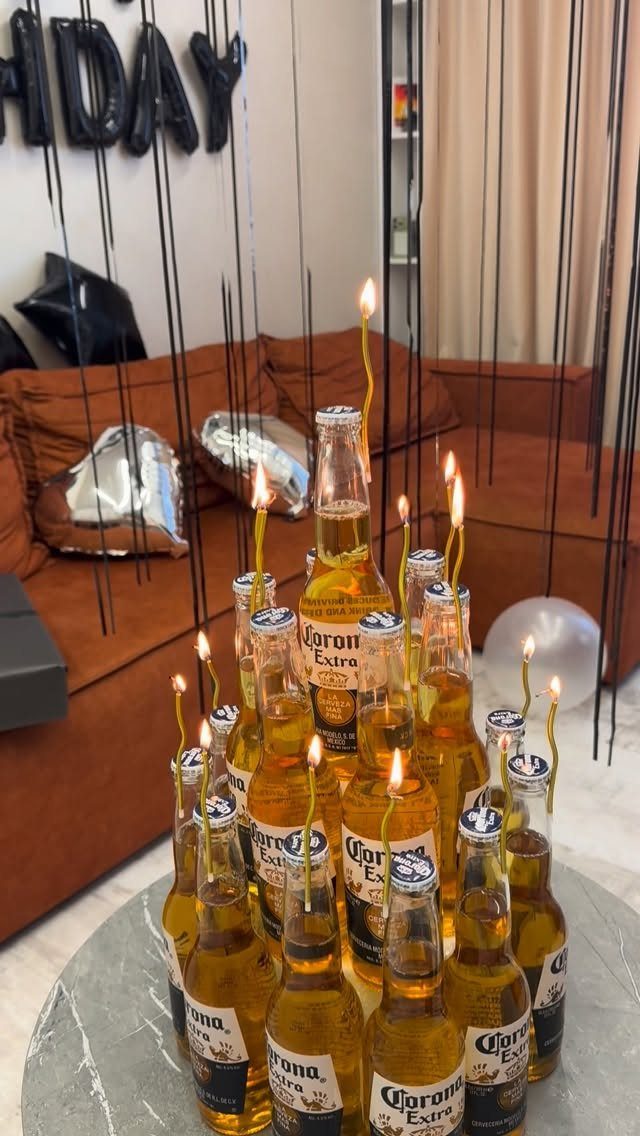 Corona beer bottles with lit candles on a table with birthday decorations
