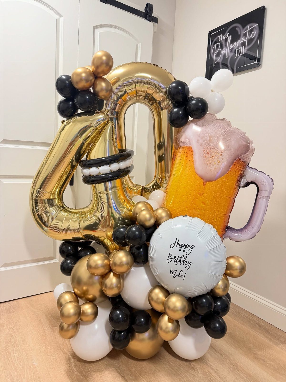 Gold number 40 balloons with a beer mug balloon and black and gold balloons.