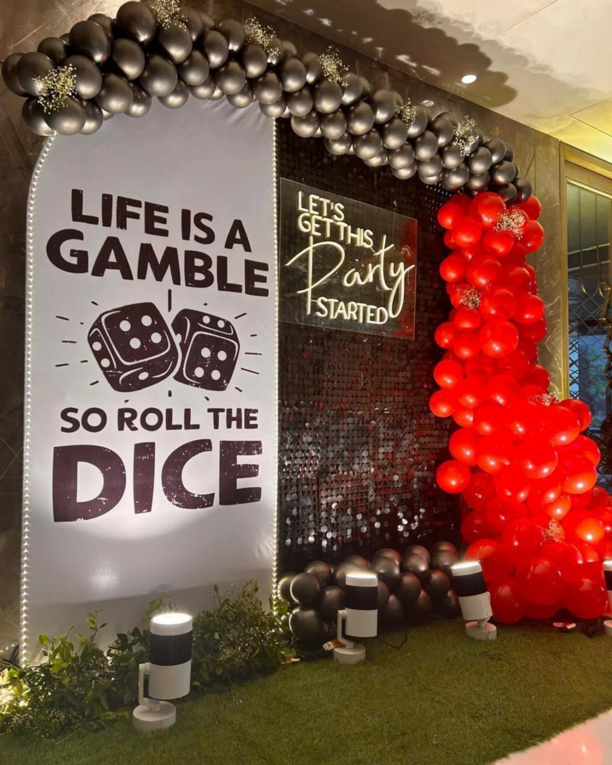 Casino themed party decorations with red and black balloons and gambling themed banners.