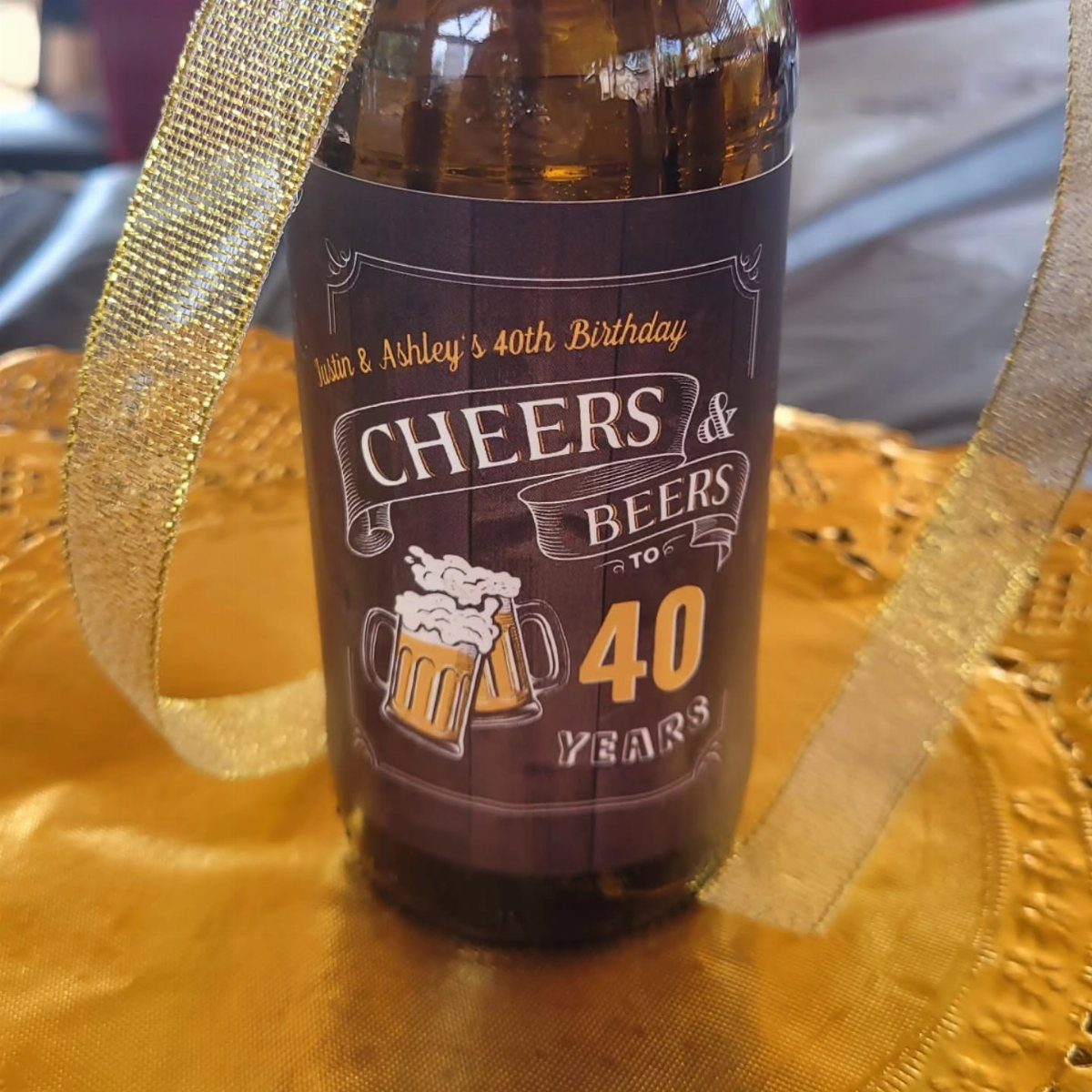 Beer bottle with custom 40th birthday label wrapped in gold glittery ribbon.