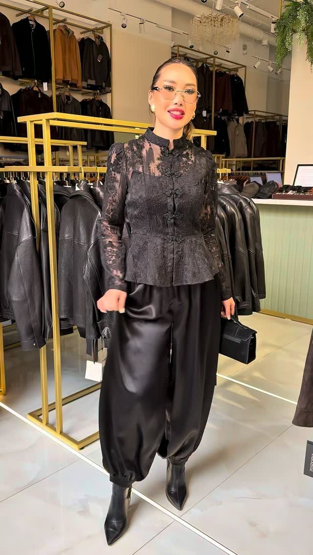 Plus-size woman wearing a black lace top and satin trousers in a store