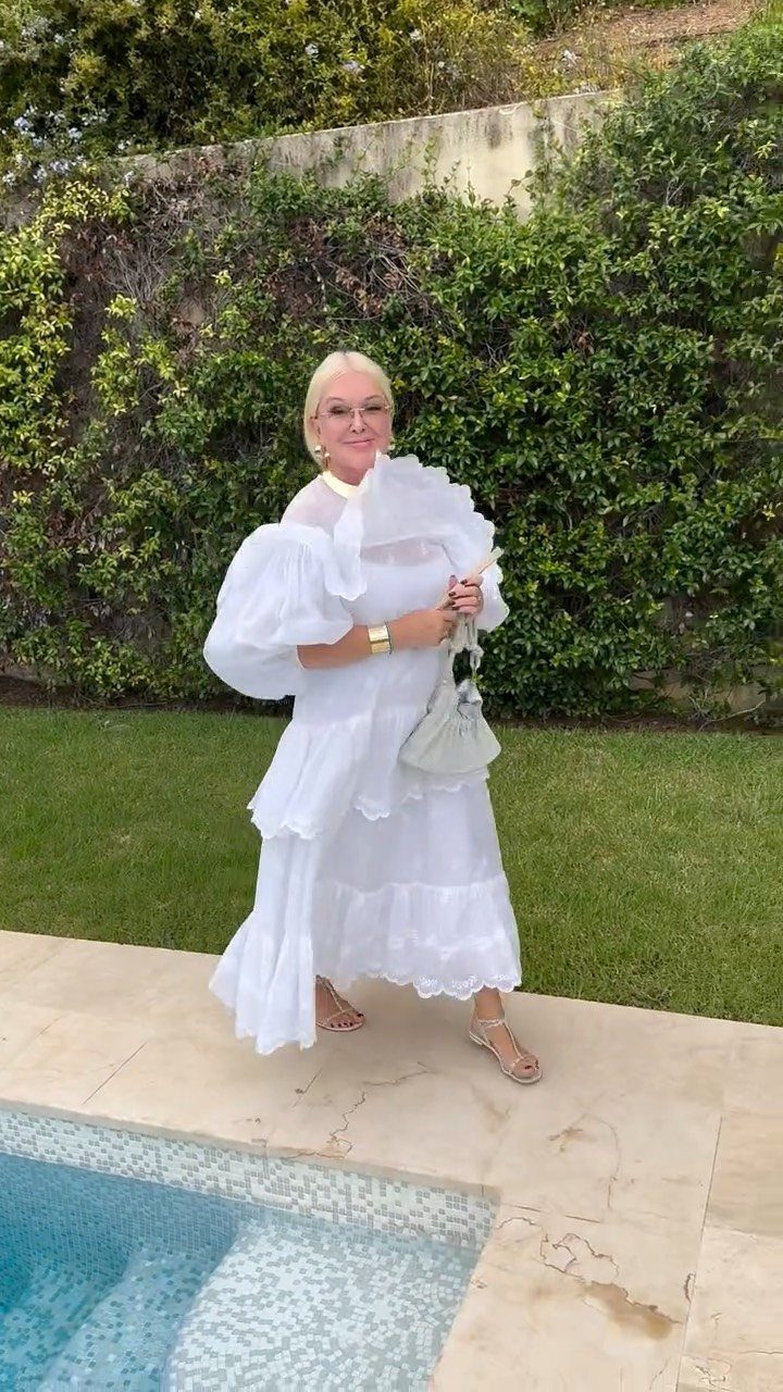 Woman in a white tiered maxi dress with puff sleeves standing by a pool