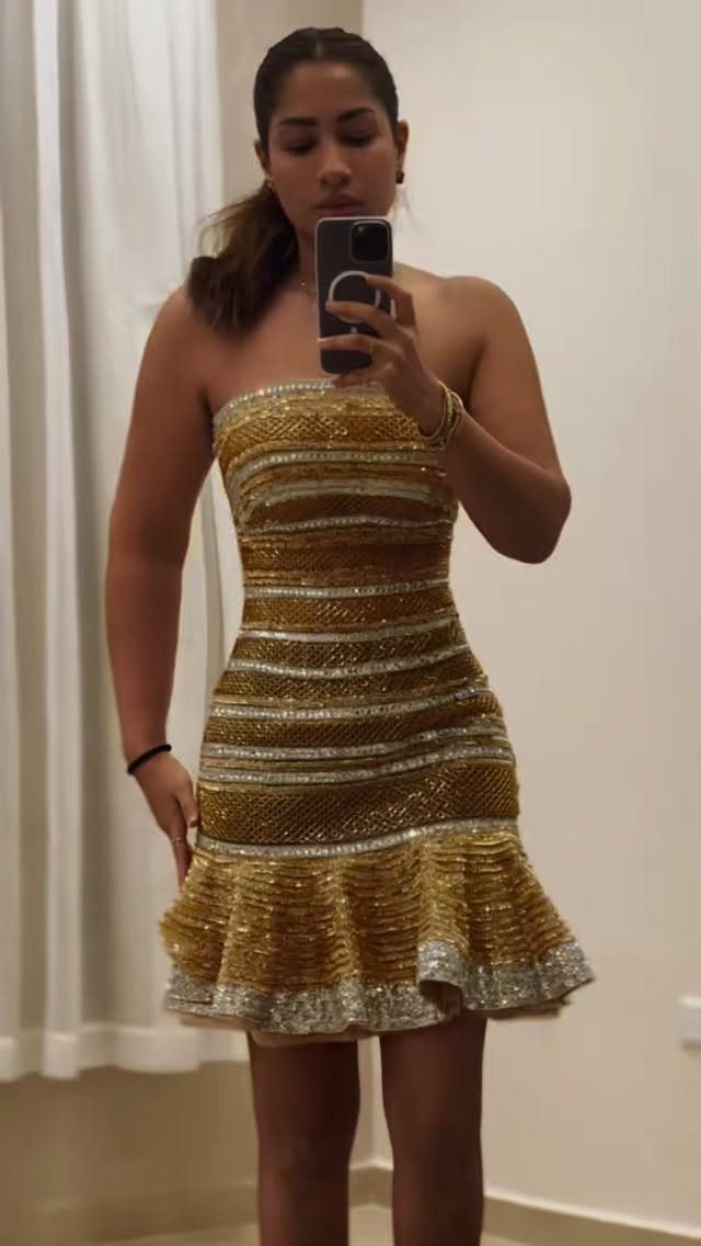 Woman in a gold and silver sequined strapless mini dress with ruffled hem.