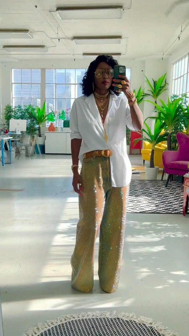 Plus-size woman wearing a white shirt and gold sequined wide-leg trousers in a studio.