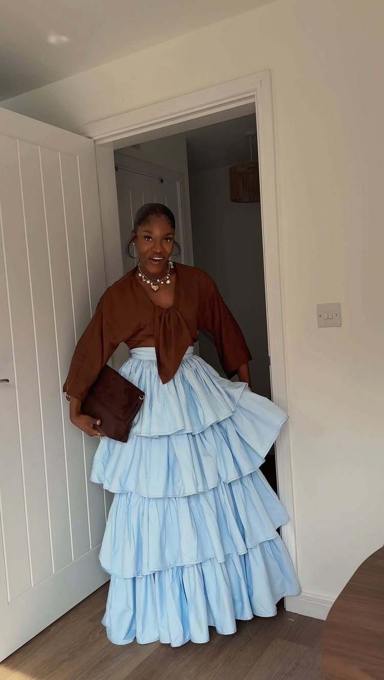 Woman wearing a brown tie-front top and a light blue tiered maxi skirt.