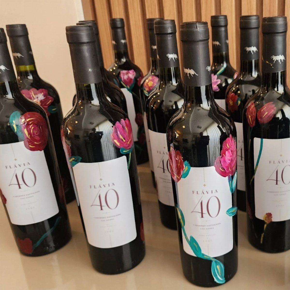 Wine bottles decorated with painted flowers and labels for a 40th birthday celebration.