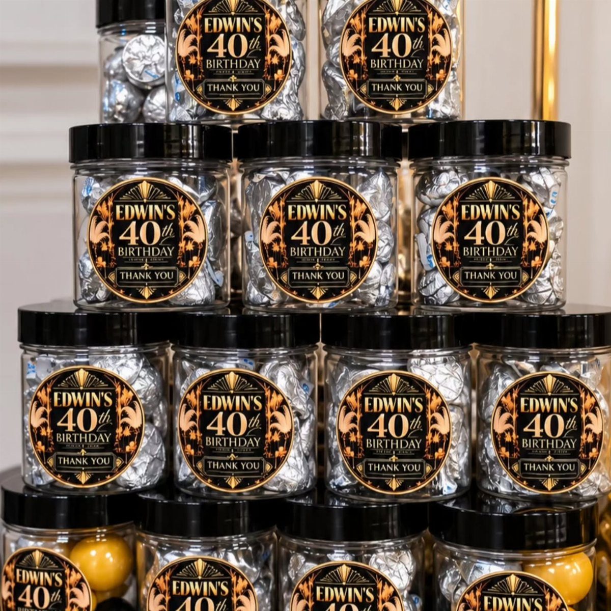 Clear jars filled with silver candies and custom 40th birthday labels stacked together.