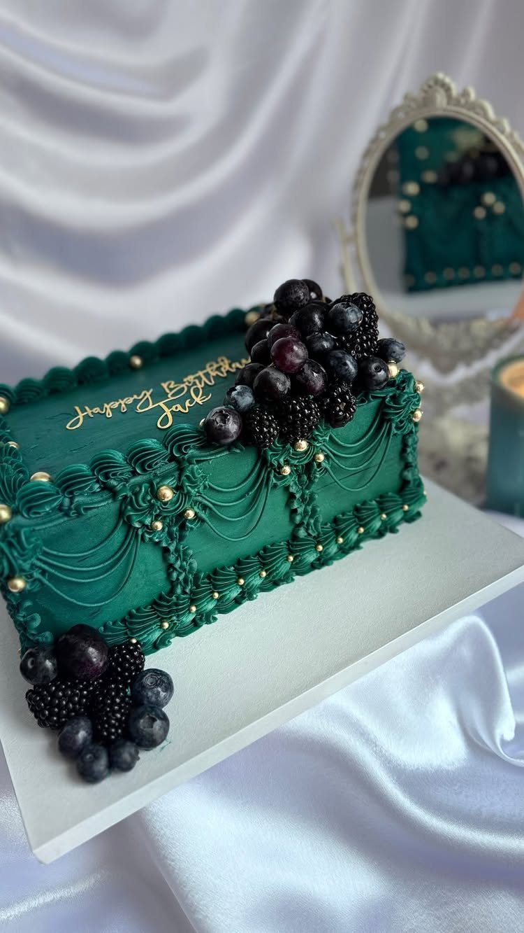 Green rectangular sheet cake with gold pearls, berries, and gold cursive birthday lettering.