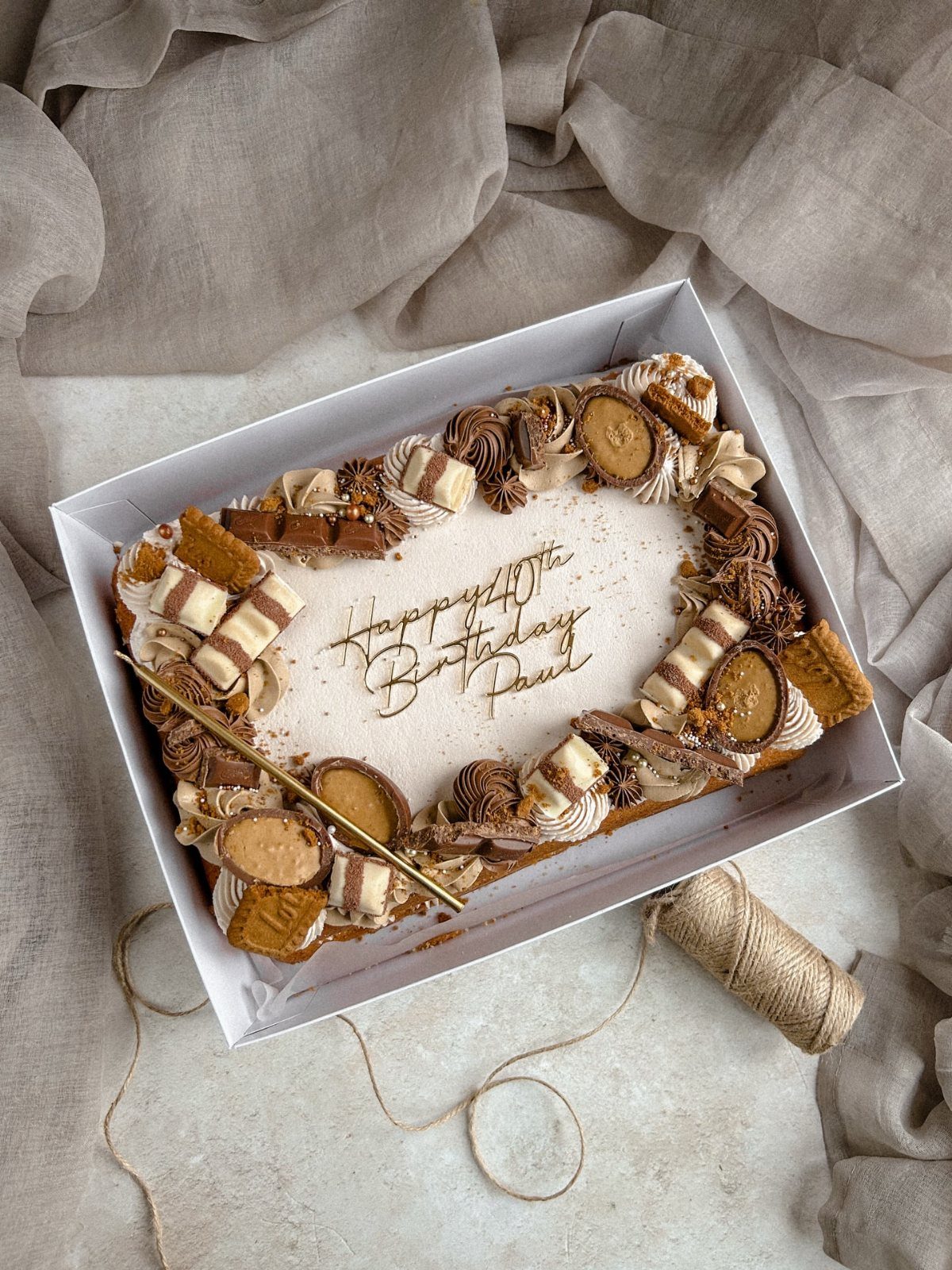 Rectangular birthday sheet cake with white frosting, chocolate decorations, and gold 40th birthday text.