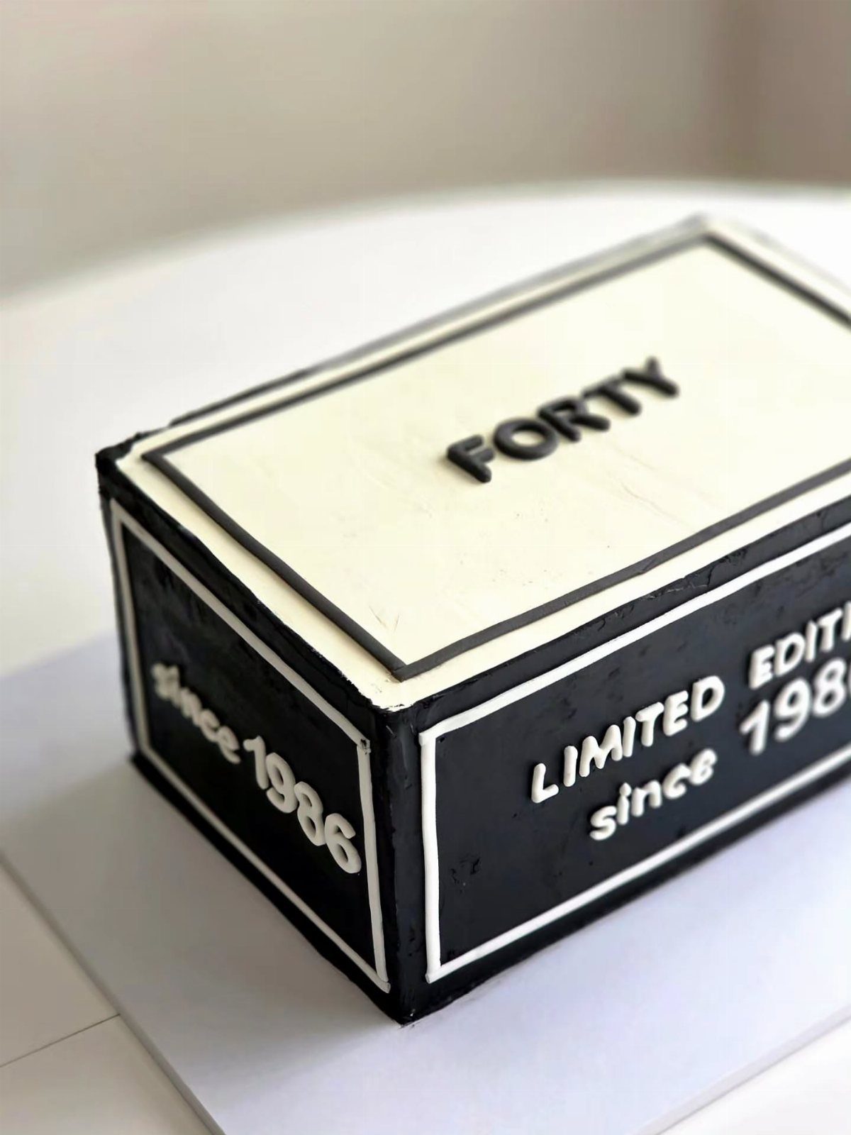 Rectangular shoebox cake with black and white frosting and 'FORTY' written on top.