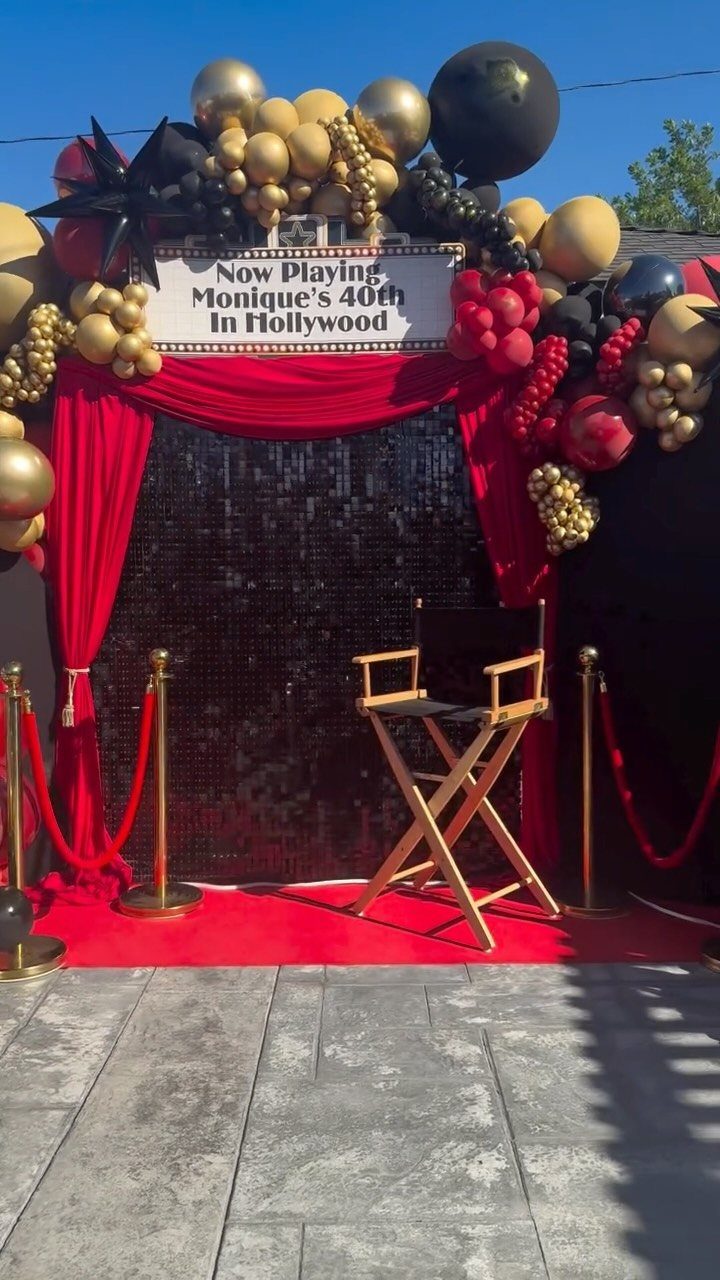 Hollywood party setup with red carpet, director's chair, and gold and black balloons.