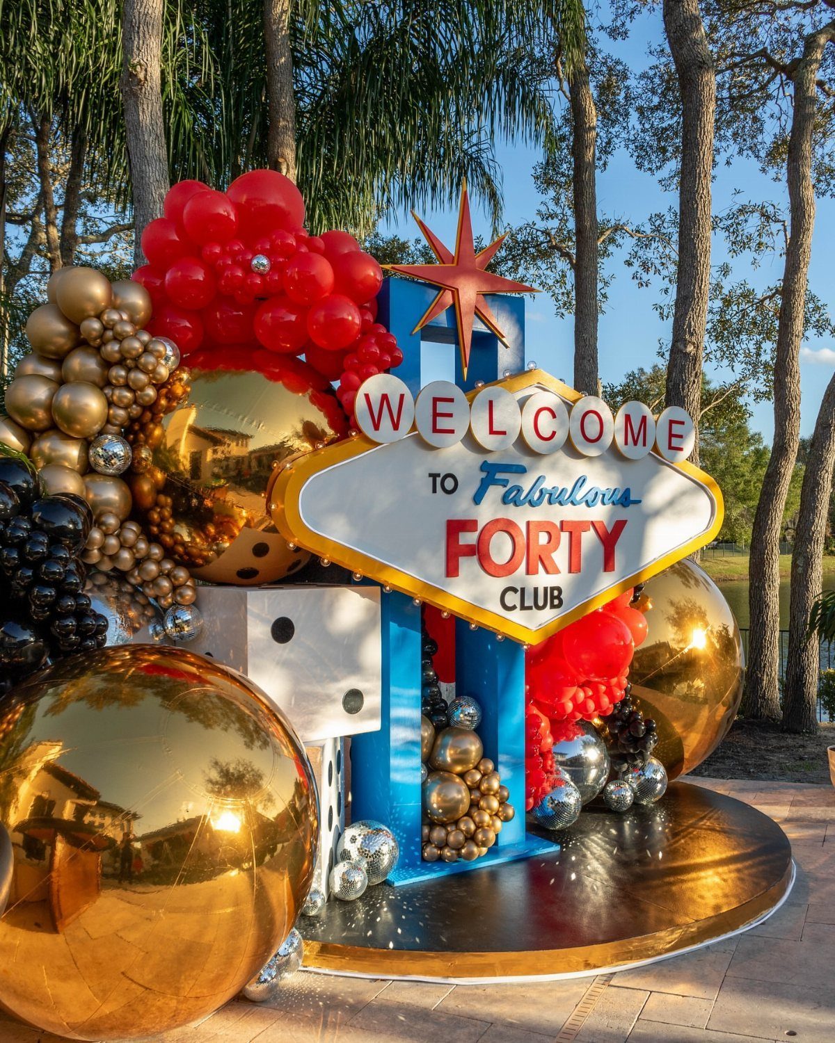 Las Vegas style birthday display with red and gold balloons and forty sign.