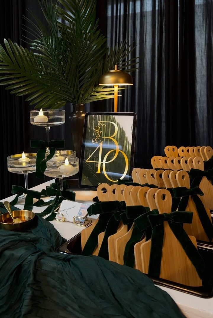 Elegant 40th birthday party decor with gold accents, green velvet ribbons, and candles.