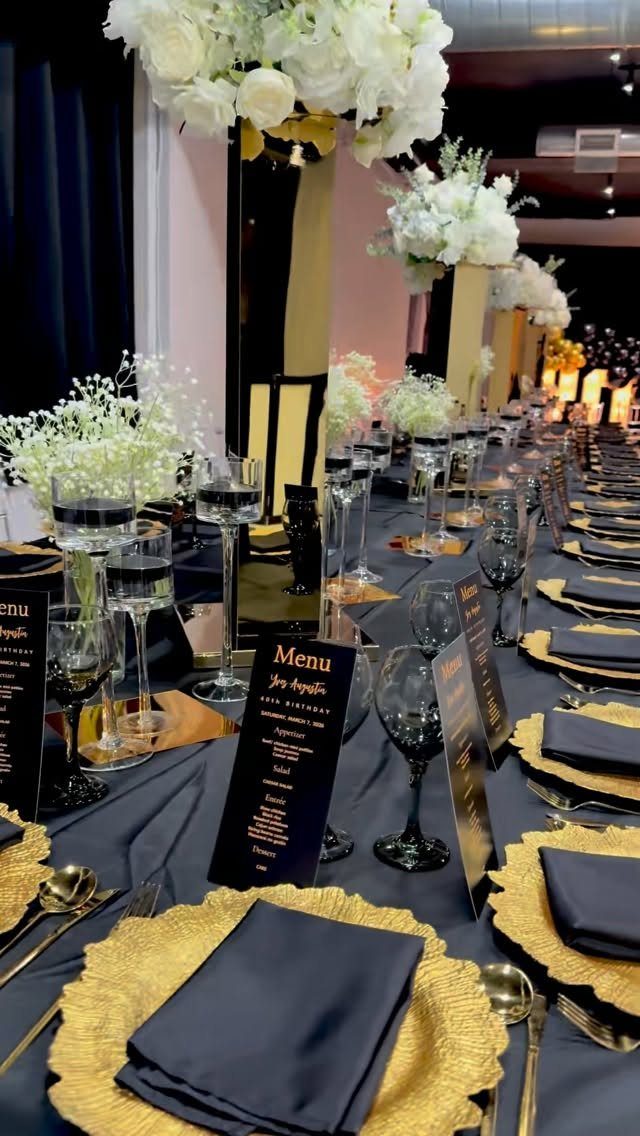 Formal banquet table setting with gold plates, navy napkins, and white floral centerpieces.