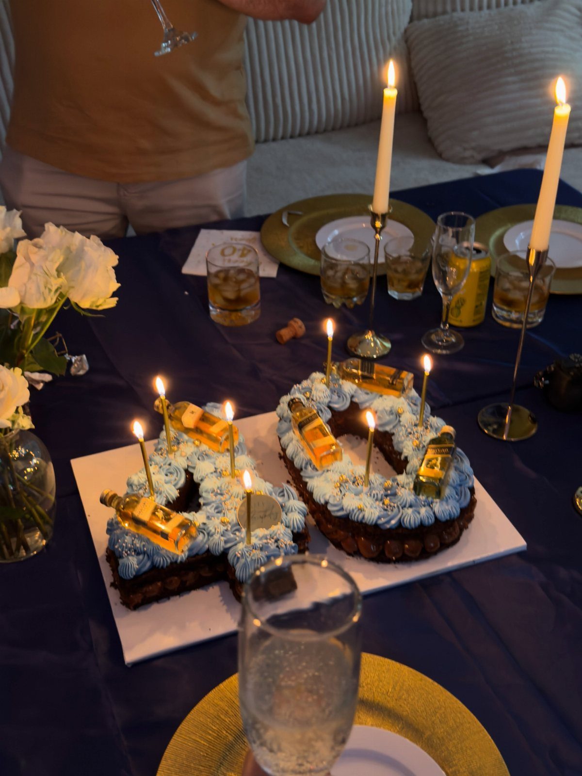 Number 40 chocolate cake with blue frosting and gold bottles on blue table