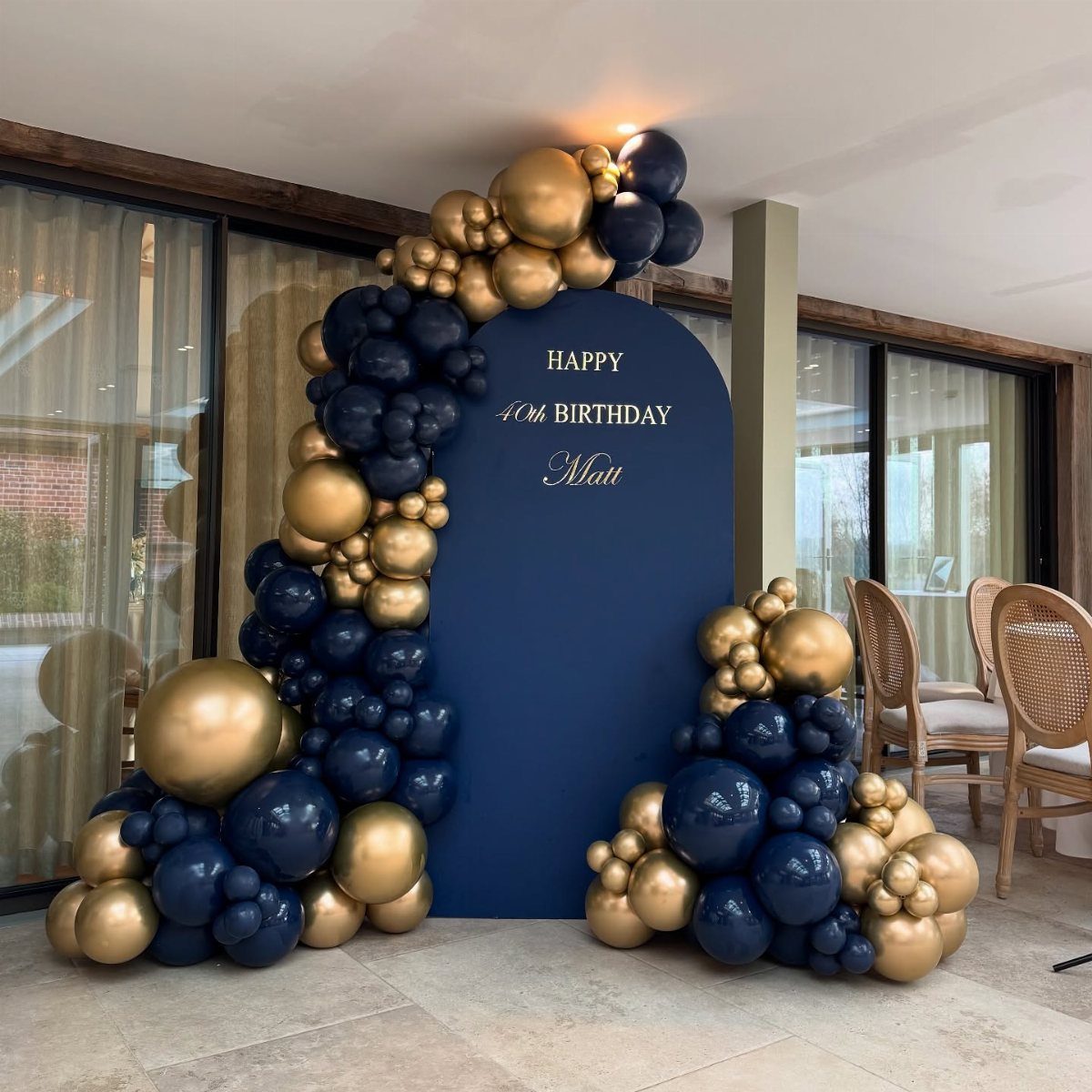Navy blue arched backdrop with gold and navy balloons for a 40th birthday.