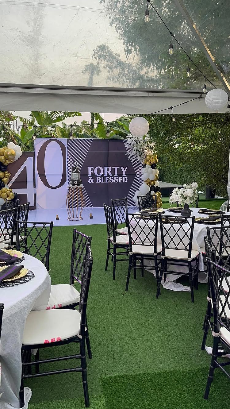 Outdoor 40th birthday party setup with black chairs and a Forty and Blessed backdrop