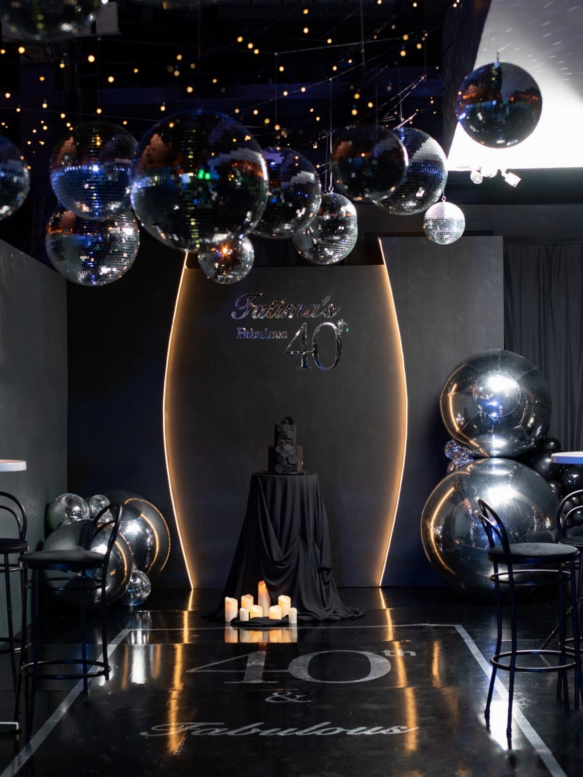 Elegant black and silver 40th birthday party decor with mirrored balloons and cake.