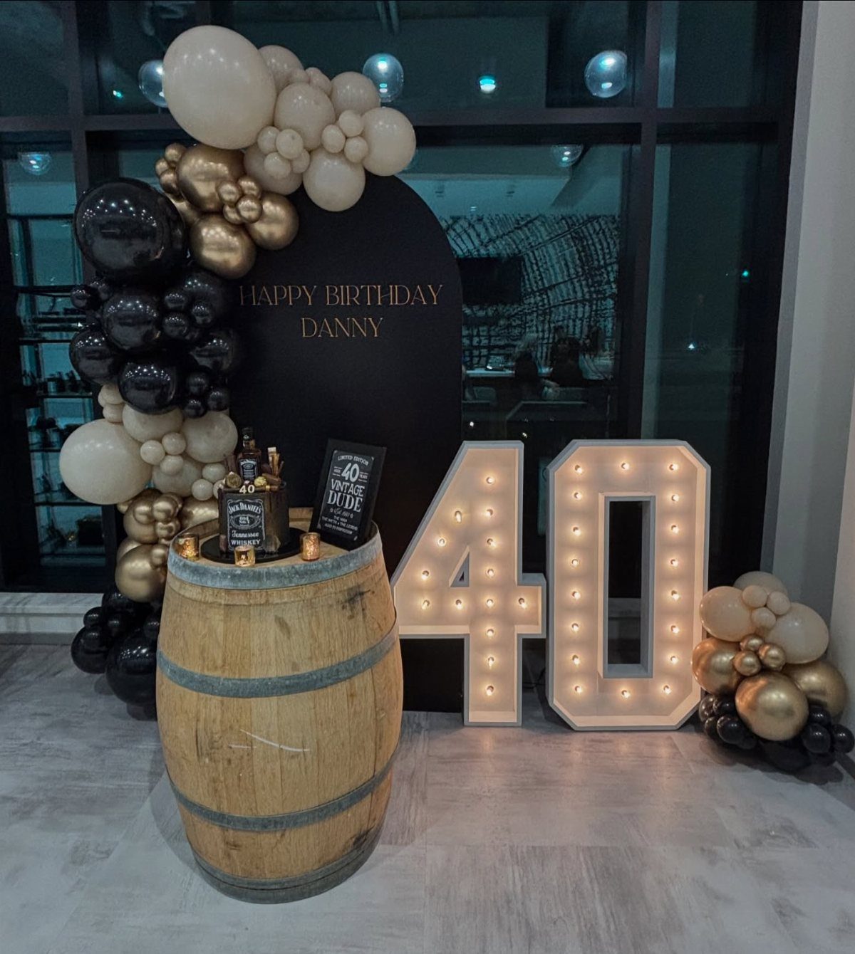 Wooden barrel with whiskey bottles and large glowing 40 numbers for a birthday.