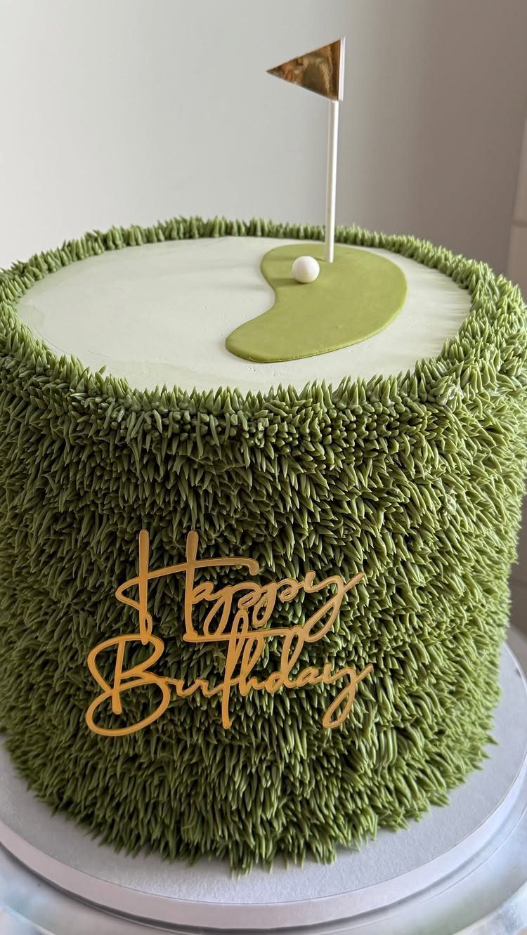 Golf themed birthday cake with green grass frosting and a gold flag pin.