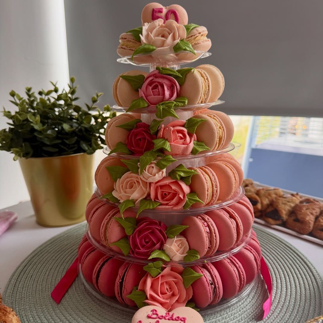 Macaron tower with pink and peach macarons decorated with frosting roses and number 50.