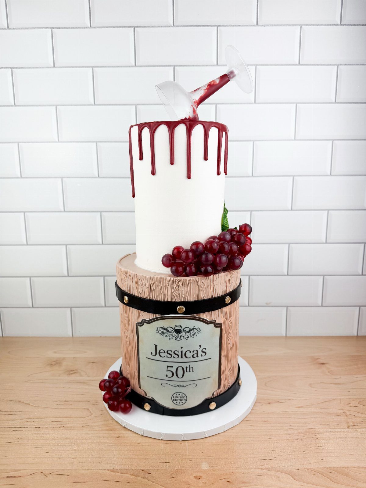 Two-tier cake with a wine barrel base and red drip top tier.