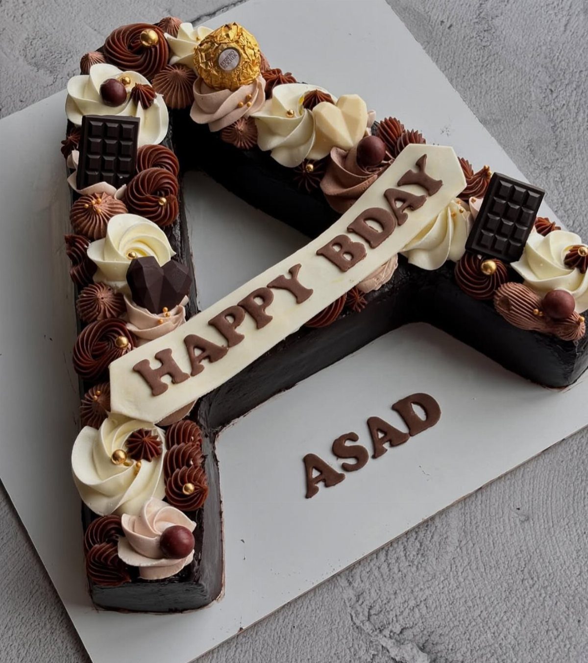 Chocolate cake shaped like the letter A with frosting and Happy Bday plaque