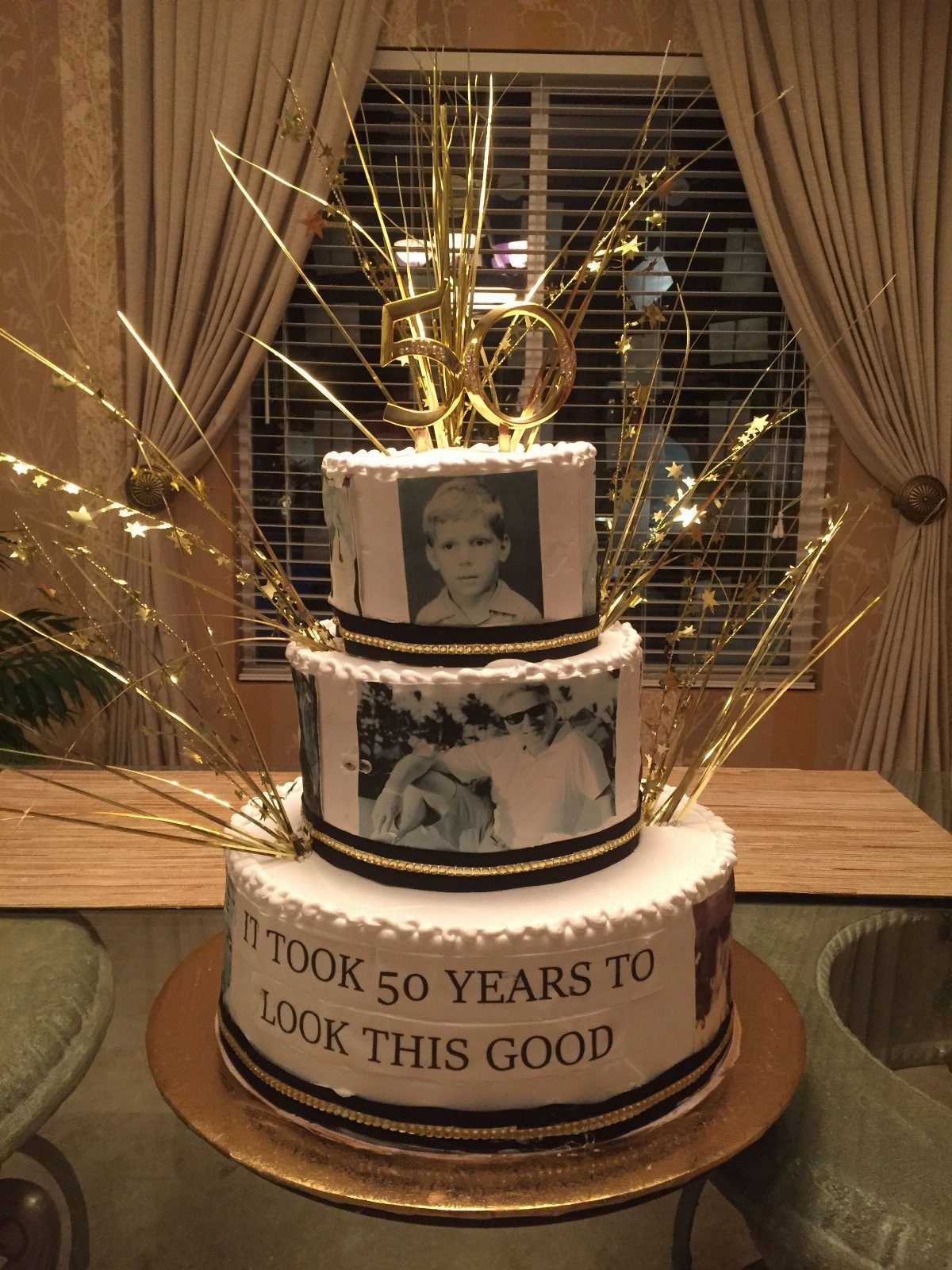 Three-tier white birthday cake with edible photos, gold toppers, and aging joke text.