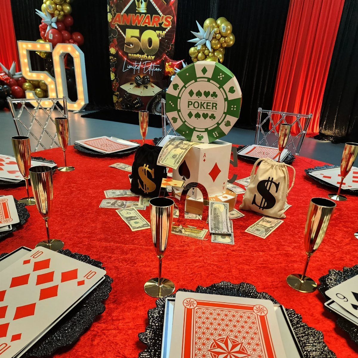 Poker themed birthday table with red felt, giant cards, and gold glasses