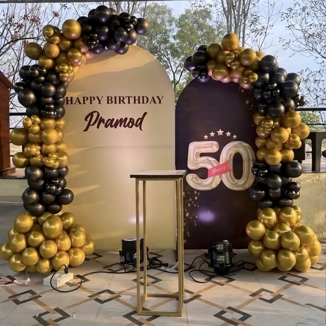 Gold and black balloon arches framing a custom birthday banner for Pramod.