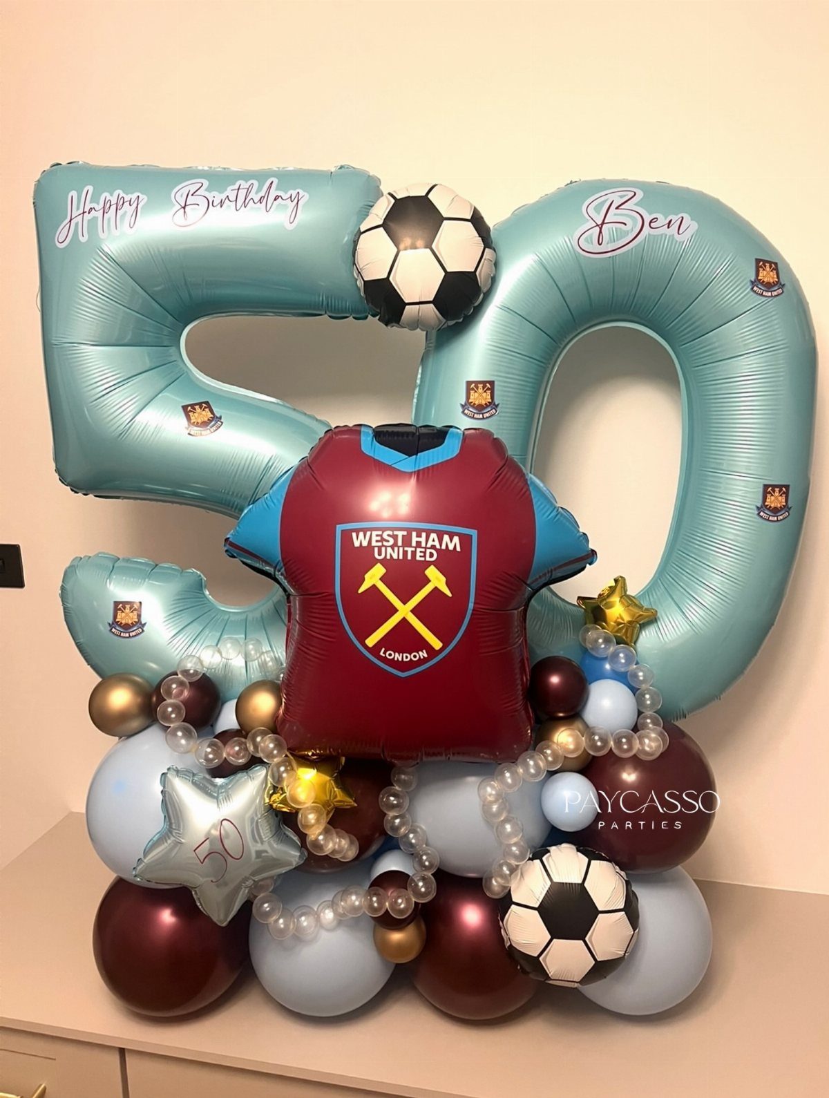 Balloon arrangement with number 50, a West Ham United jersey, and soccer balls.