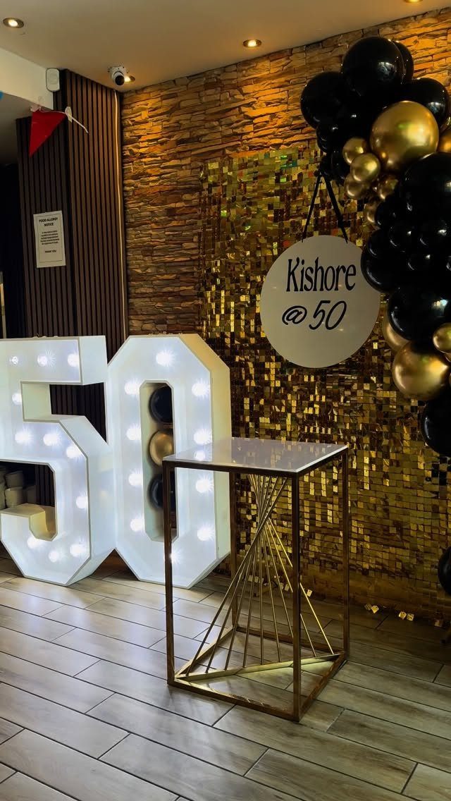 Illuminated number 50 decorations with gold sequins and black and gold balloons.