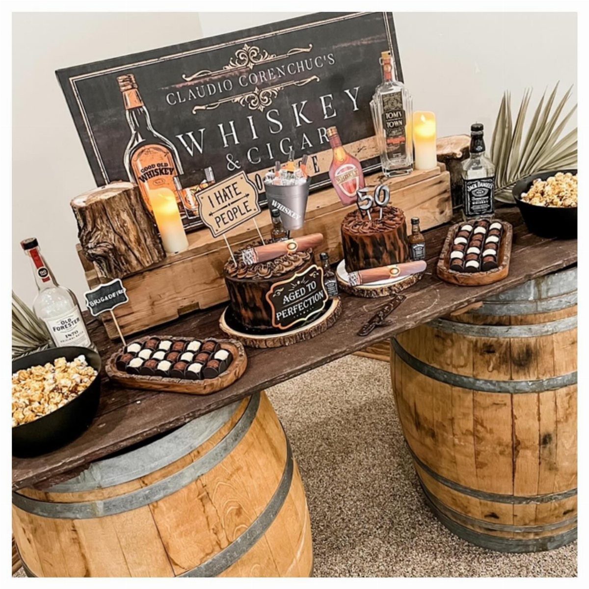 Whiskey and cigar themed birthday display with cakes and bottles on wooden barrels